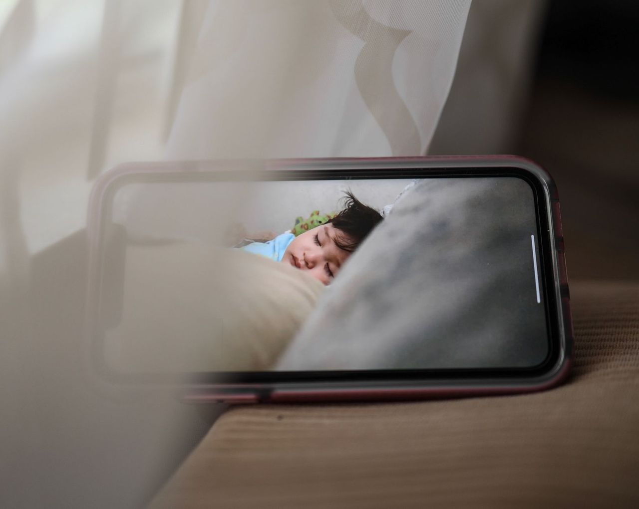Parent looking at a baby monitor screen on a bedside table at night