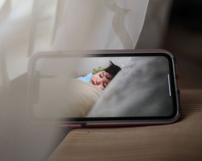 Parent looking at a baby monitor screen on a bedside table at night