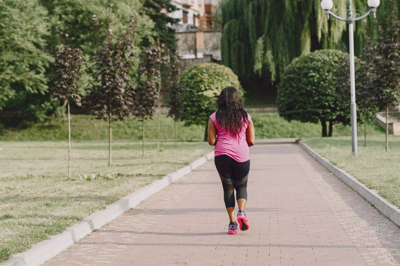 woman running park path morning
